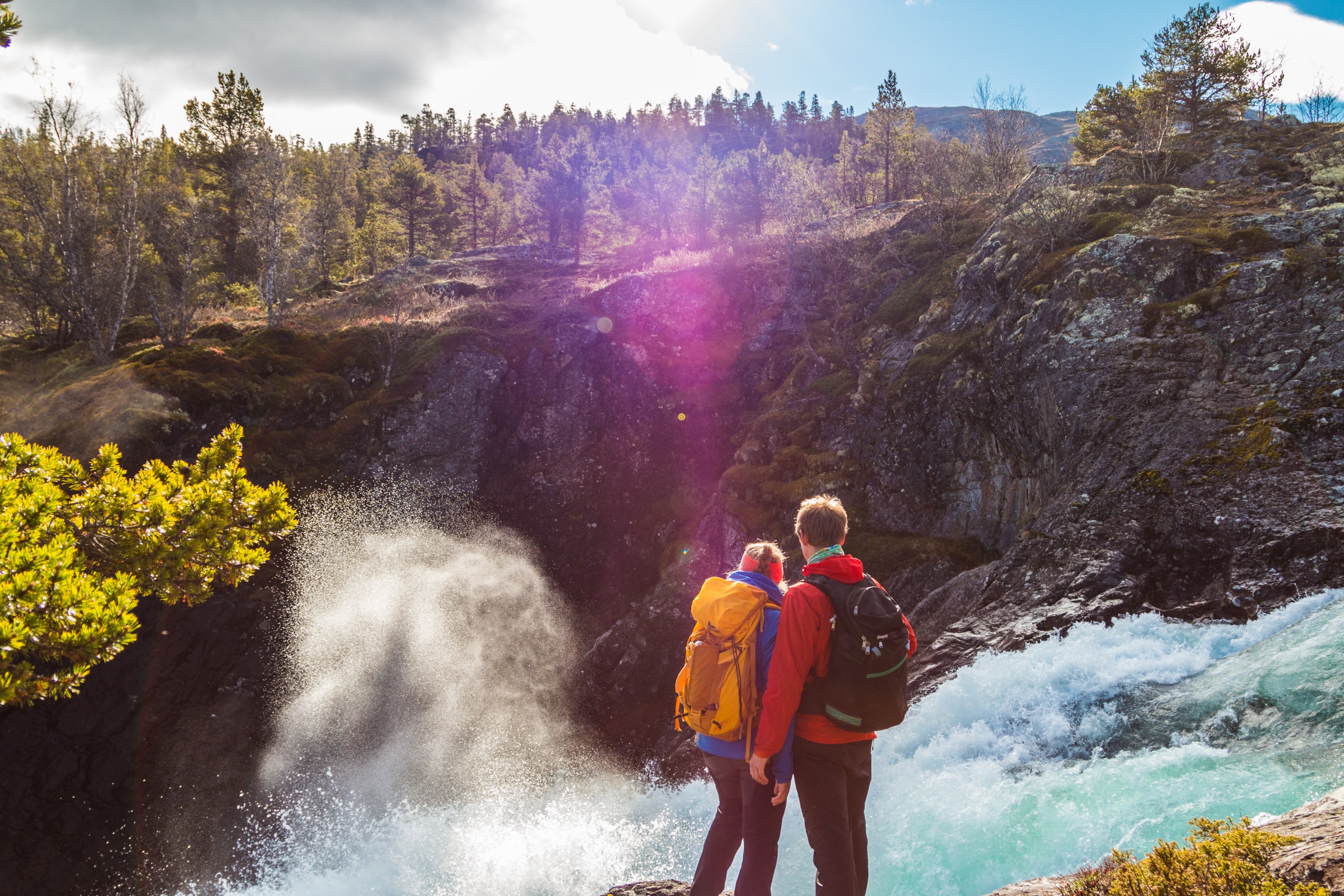 Ein Paar mit Rucksäcken schaut auf einen Wasserfall